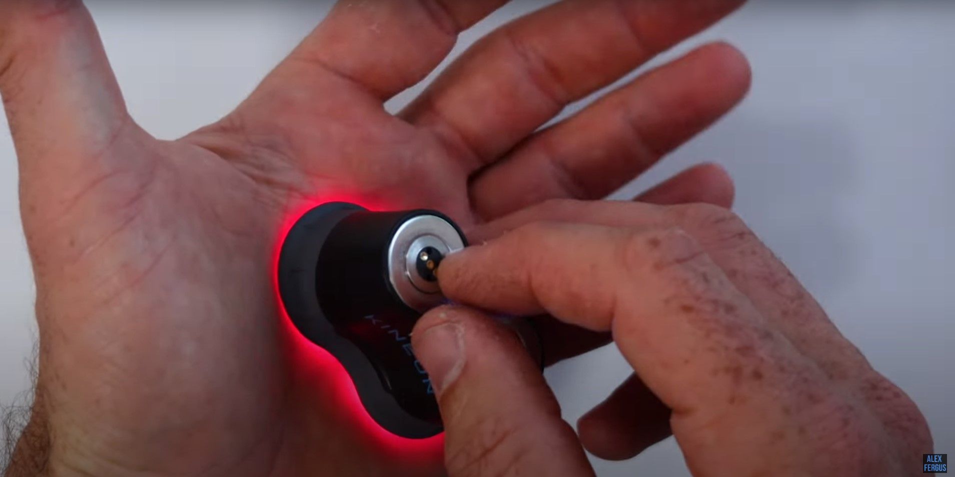 Alex Fergus holding a targeted red light therapy laser against his palm