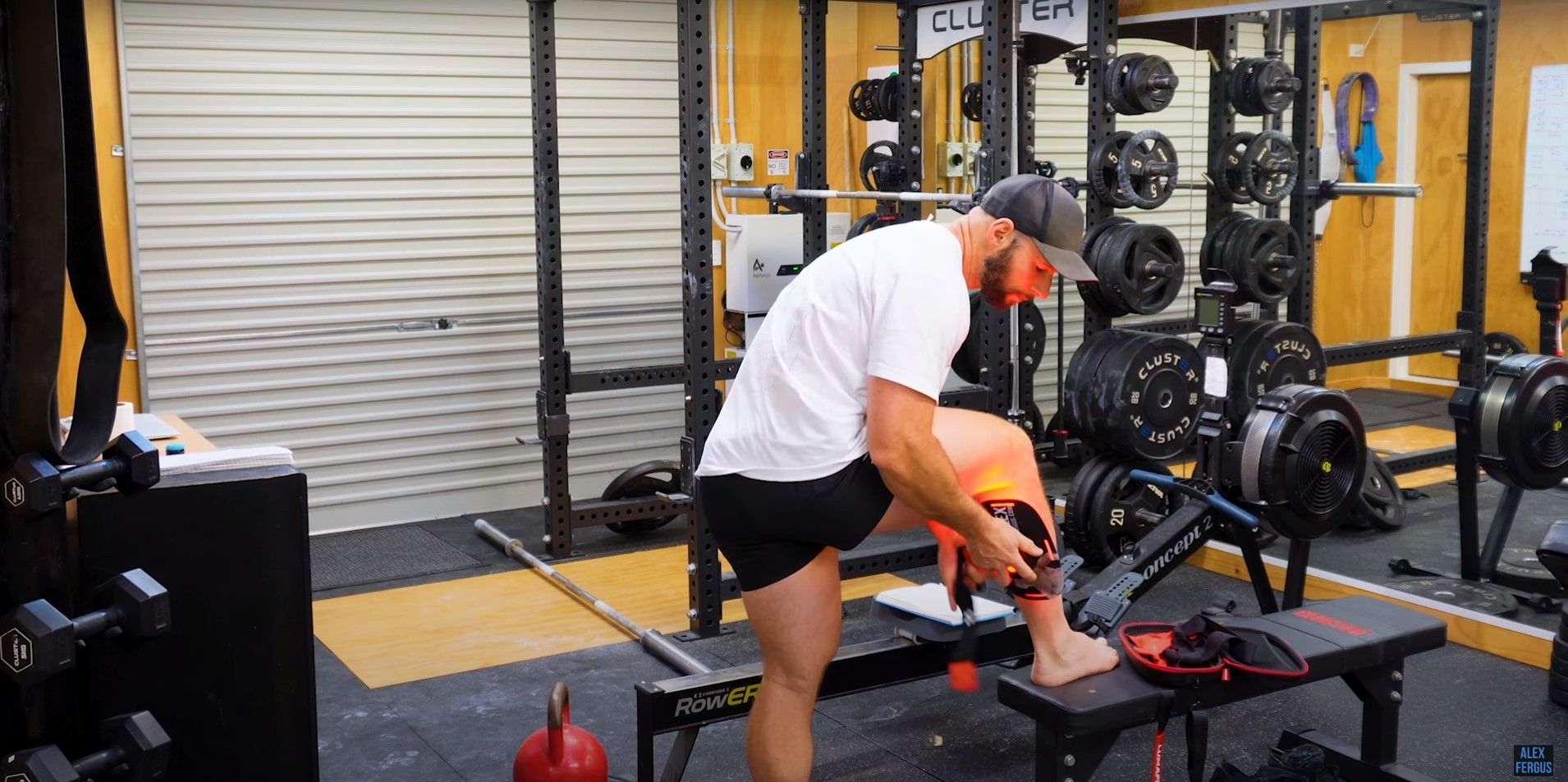 Alex Fergus using targeted red light therapy on his calf muscle in his home gym