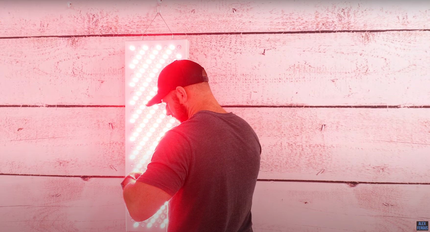 Alex using the Rouge Pro G3 red light therapy panel hanging on his wall